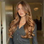 Woman with long, wavy hair standing indoors in a casual setting.